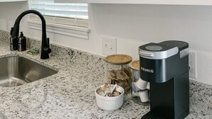 A kitchen with a granite countertop, a coffee maker, a sink, and framed pictures on the wall. - Elegant studio near downtown (Abilene)
