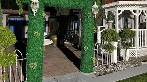 A gated entrance with a green hedge archway, a white building with a red roof, and a pathway leading to the building. - Do you want to select a perfect place to know Miami?. This is R and R Hostal.  (Miami)