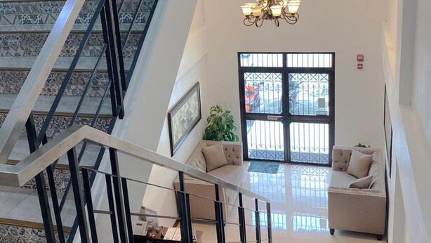 Ampla sala de estar com escada, lustre e sofá.