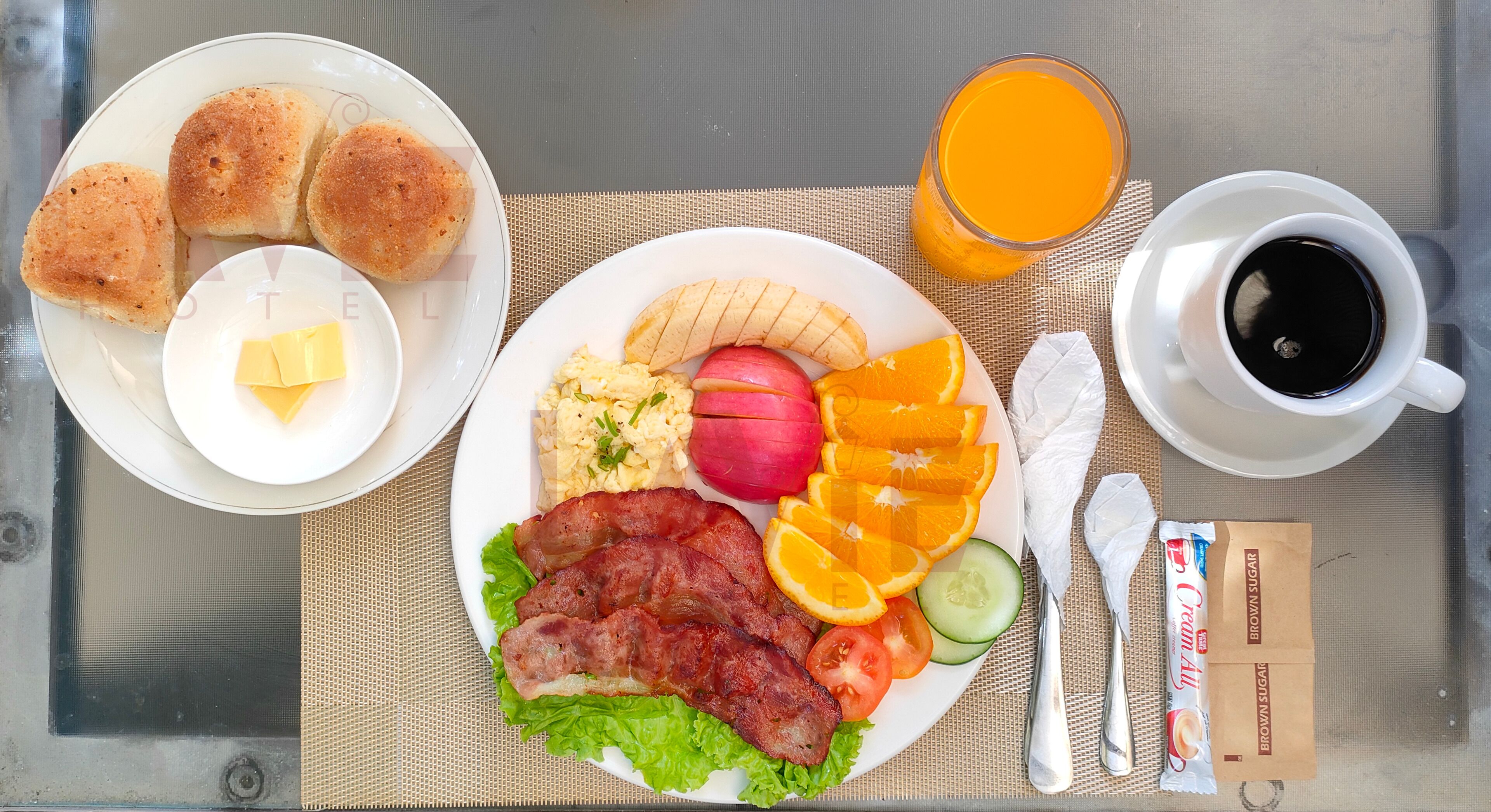 A breakfast tray with eggs, bacon, toast, orange slices, and a glass of orange juice on a table.