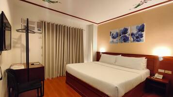 Une chambre d’hôtel équipée d’un lit, d’un bureau, d’une chaise, d’un téléphone et d’un climatiseur fixé au mur.