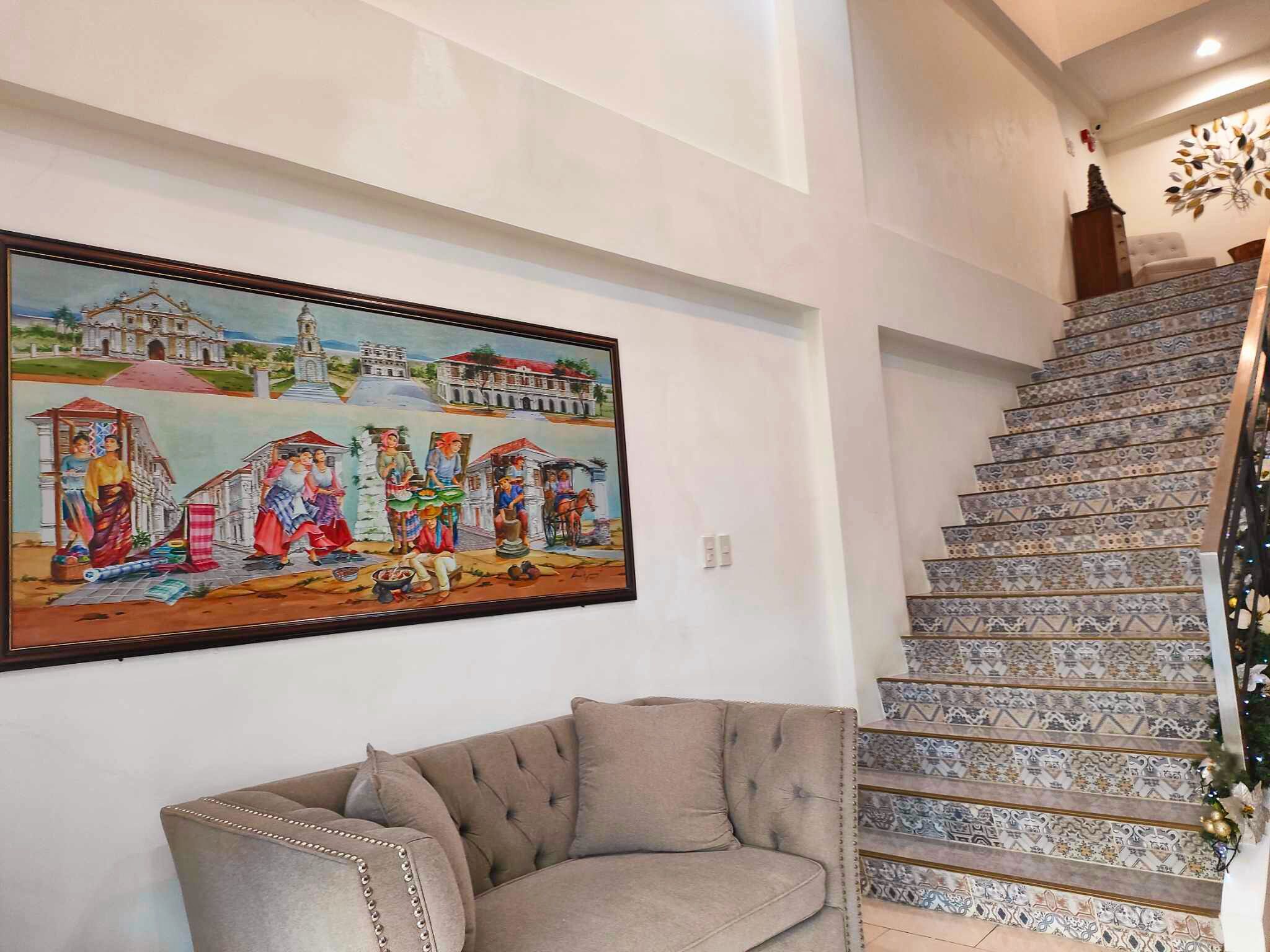 Una escalera con baldosas estampadas y un cuadro enmarcado de una escena tradicional en la pared.