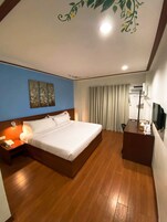 Una habitación de hotel con una cama grande, un escritorio, una silla, un teléfono y una televisión.