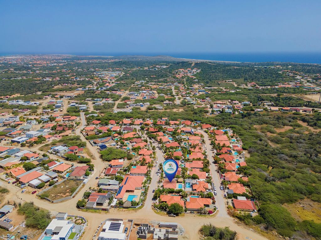 An aerial view of a residential area with houses, roads, and greenery.
