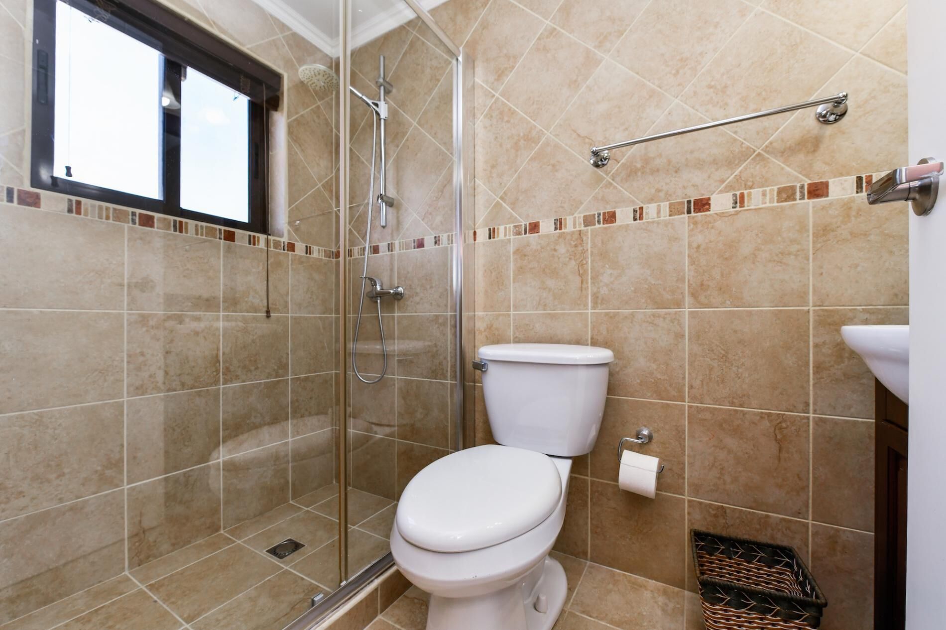 A bathroom with a glass-enclosed shower, a toilet, and a sink.