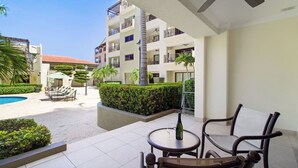 A hotel courtyard with a pool, lounge chairs, and a table with a bottle and glass.