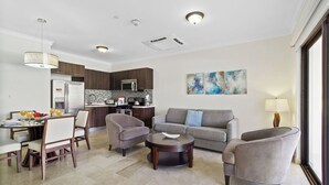 A modern living room with a grey sofa, two armchairs, a coffee table, and a dining area with a table and chairs.
