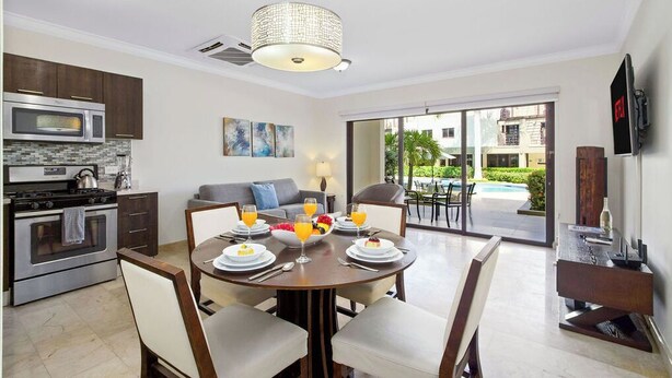 A modern kitchen with a dining area, a large window, and a view of a swimming pool.