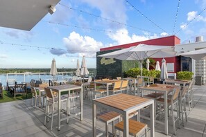 An outdoor terrace with tables and chairs, umbrellas, and a view of the water. - Ocean View Wraparound Balcony and Rooftop Pool-CS1 (Hollywood)