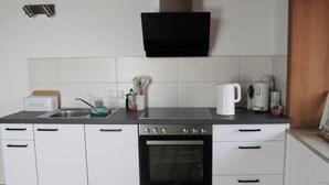 Une cuisine moderne avec des meubles blancs, un four encastré, un évier et une machine à café.