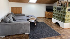Un salon chaleureux avec un canapé gris, une petite table ronde, un téléviseur et un meuble décoratif.