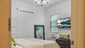 Ein Schlafzimmer mit einem Bett, einem Schminktisch, einem Spiegel und einem Bild an der Wand.