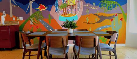 Enjoy meals in a vibrant dining area with a stunning desert landscape mural and comfortable seating for four.