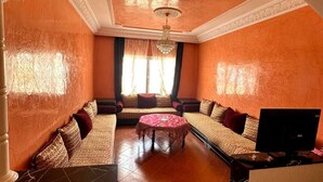 Amplia sala de estar con un conjunto de sofás, una mesa de centro y un televisor.