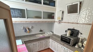 Una cocina compacta con armarios blancos, un microondas, un tostador y una tetera.