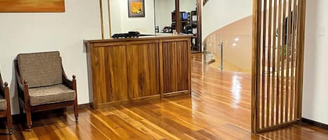 Un área de recepción con un escritorio de madera, una silla y una escalera que sube a otro nivel.