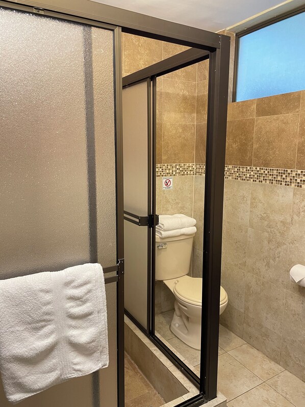 A bathroom with a glass-enclosed shower, a toilet, and a towel rack. - NASS Loft Atahualpa (Cuenca)
