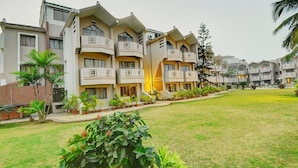 A multi-story hotel with balconies, a well-maintained lawn, and potted plants. - Hotel Sagar Tarang (Berries Group) (Puri)