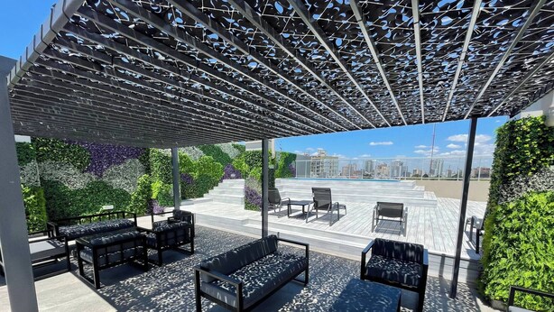 Tagterrasse med udendørs møbler, en pergola og udsigt over byen.