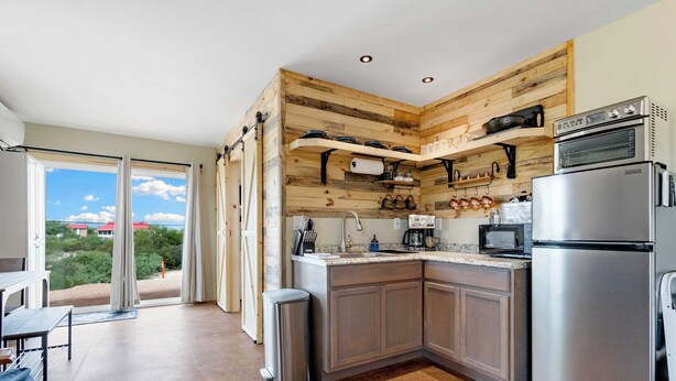 A modern kitchen with wooden accents, stainless steel appliances, and a view to the outside.
