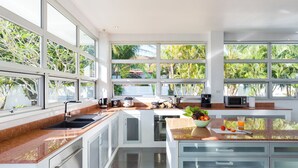 A modern kitchen with large windows, stainless steel appliances, and a granite countertop. - Secluded Paradise Your Exclusive Villa  (Rawai)