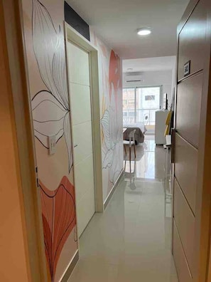A hallway with a modern design, featuring a glass door with a leaf pattern, a wall with a leaf pattern, and a clean, shiny floor.