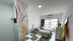A modern hotel room with a bed, a desk, and a dining area. - Studio In San Telmo La Cisterna Num2689 (Buenos Aires)