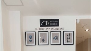 A hallway with a series of framed artworks on the wall and a ceiling light. - Studio In San Telmo La Cisterna Num2689 (Buenos Aires)