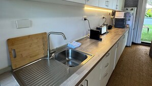 A modern kitchen with a stainless steel sink, wooden cutting board, and built-in cabinets.