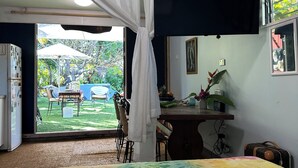 A room with a bed, a desk, a chair, and a view of an outdoor area with a table and chairs.