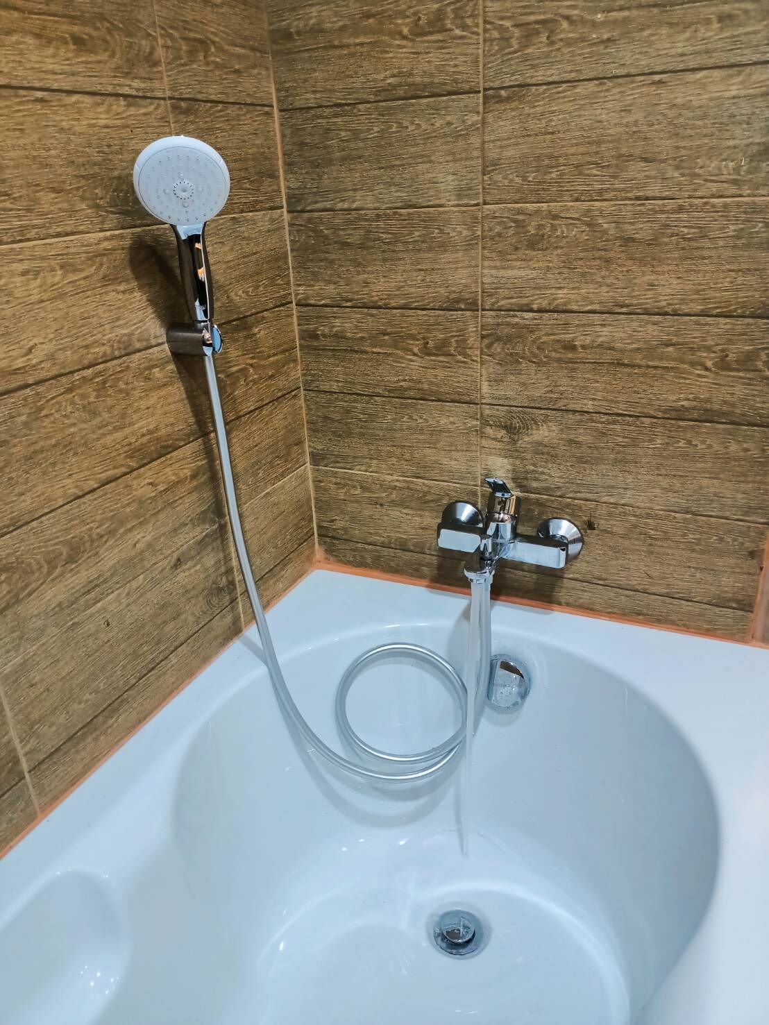 Uma banheira com chuveiro manual e torneira embutida.