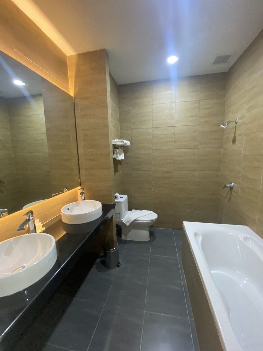 A modern bathroom with two sinks, a toilet, and a bathtub.