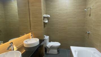 A modern bathroom with two sinks, a toilet, and a bathtub.