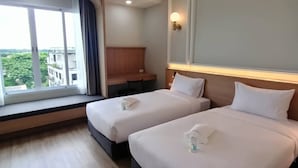 Habitación de hotel con dos camas, un escritorio y un ventanal grande con vistas a la ciudad.