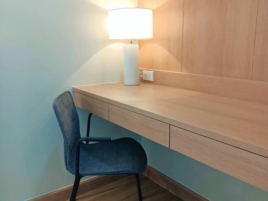 A small, modern workspace with a desk and chair, a lamp, and a wooden wall.