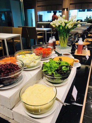 Un bufé con diversos alimentos, como huevos, frijoles, ensalada y salsas.