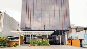Un edificio moderno con una amplia fachada de vidrio, un área de entrada cubierta y un letrero que dice 