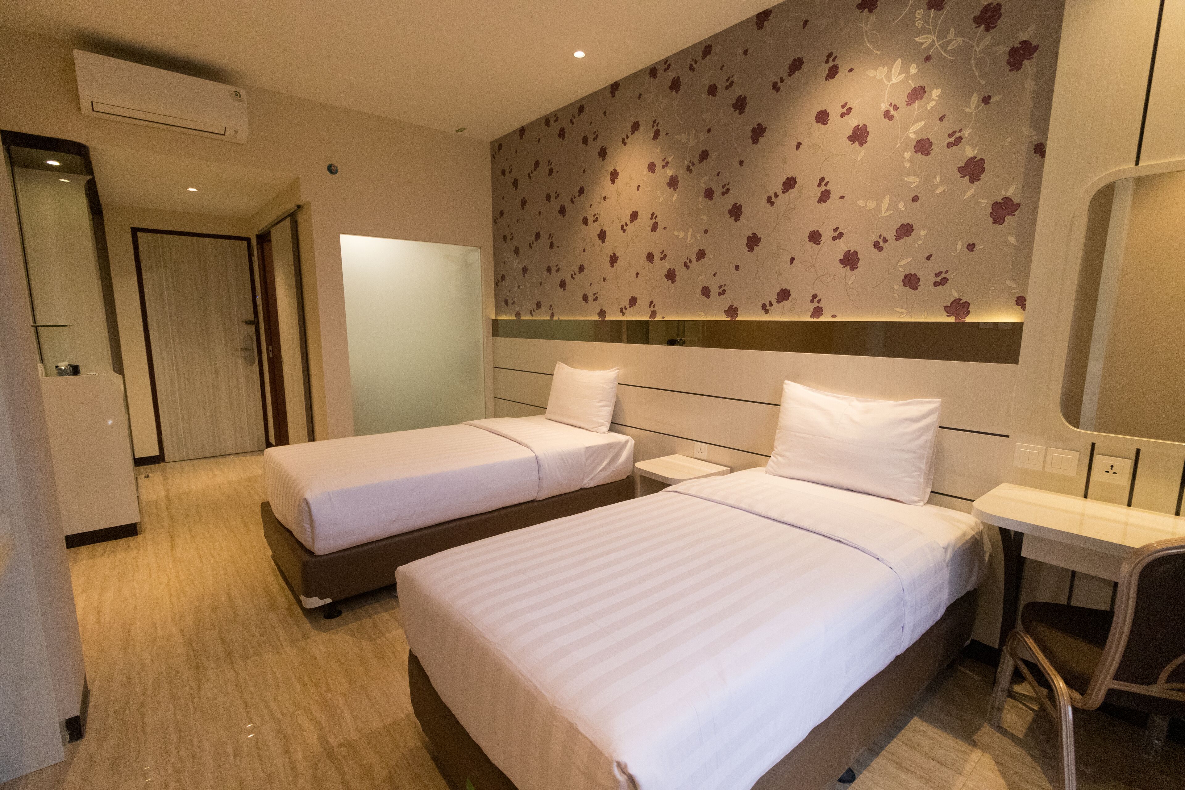 Una habitación de hotel con dos camas, un escritorio, una silla y un espejo.