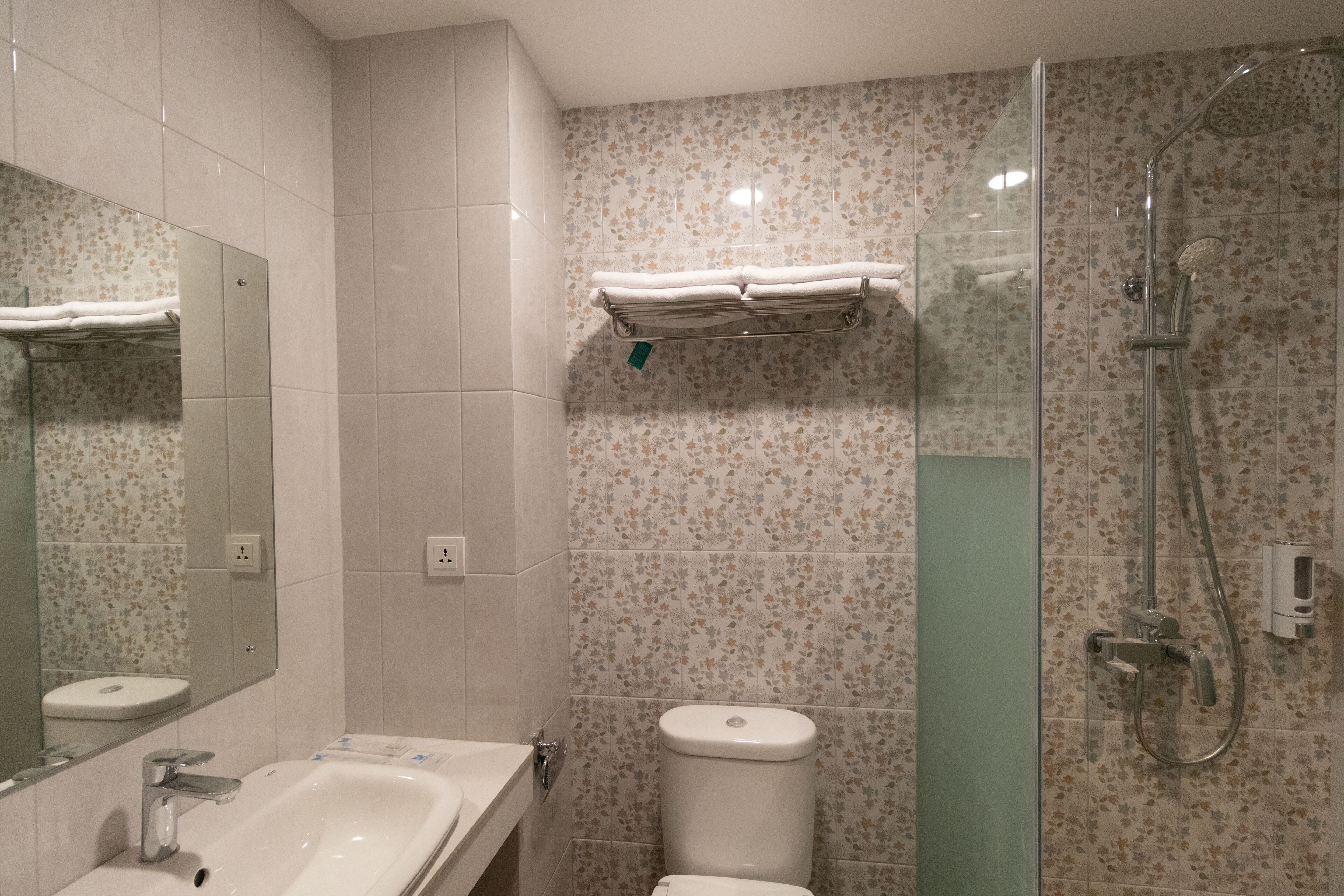 Een badkamer met een wastafel, toilet en een douchecabine met glazen wanden.