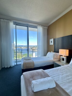 A hotel room with two beds, a view of a cityscape, and a large window with sheer curtains. - Chevron Renaissance-Resort Style Living managed by Gold Coast Premium (Surfers Paradise)