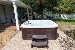 A hot tub with a wooden deck and a covered seating area. - The Fairway to Heaven (Bryan)