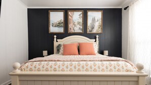 A bedroom with a bed, two wall-mounted lamps, and three framed pictures on the wall. - The Fairway to Heaven (Bryan)