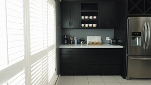 A kitchen with dark cabinets, a stainless steel refrigerator, and a window with blinds. - The Fairway to Heaven (Bryan)