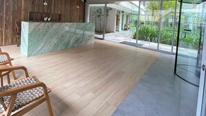 Un'accoglienza moderna con soffitto in legno, una reception in marmo e una porta in vetro che dà sull'esterno.