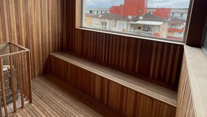 Un interno in legno con un'ampia finestra, una panca integrata e una rastrelliera in metallo.