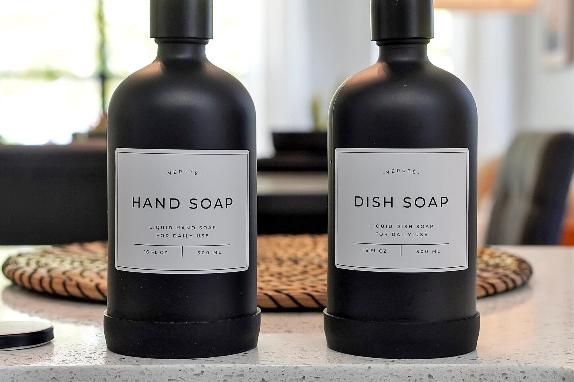 Dos botellas de jabón para manos y platos sobre una encimera.