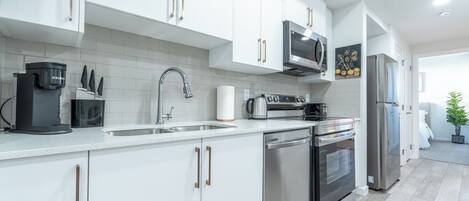 A modern kitchen with white cabinets, stainless steel appliances, and a tiled backsplash.