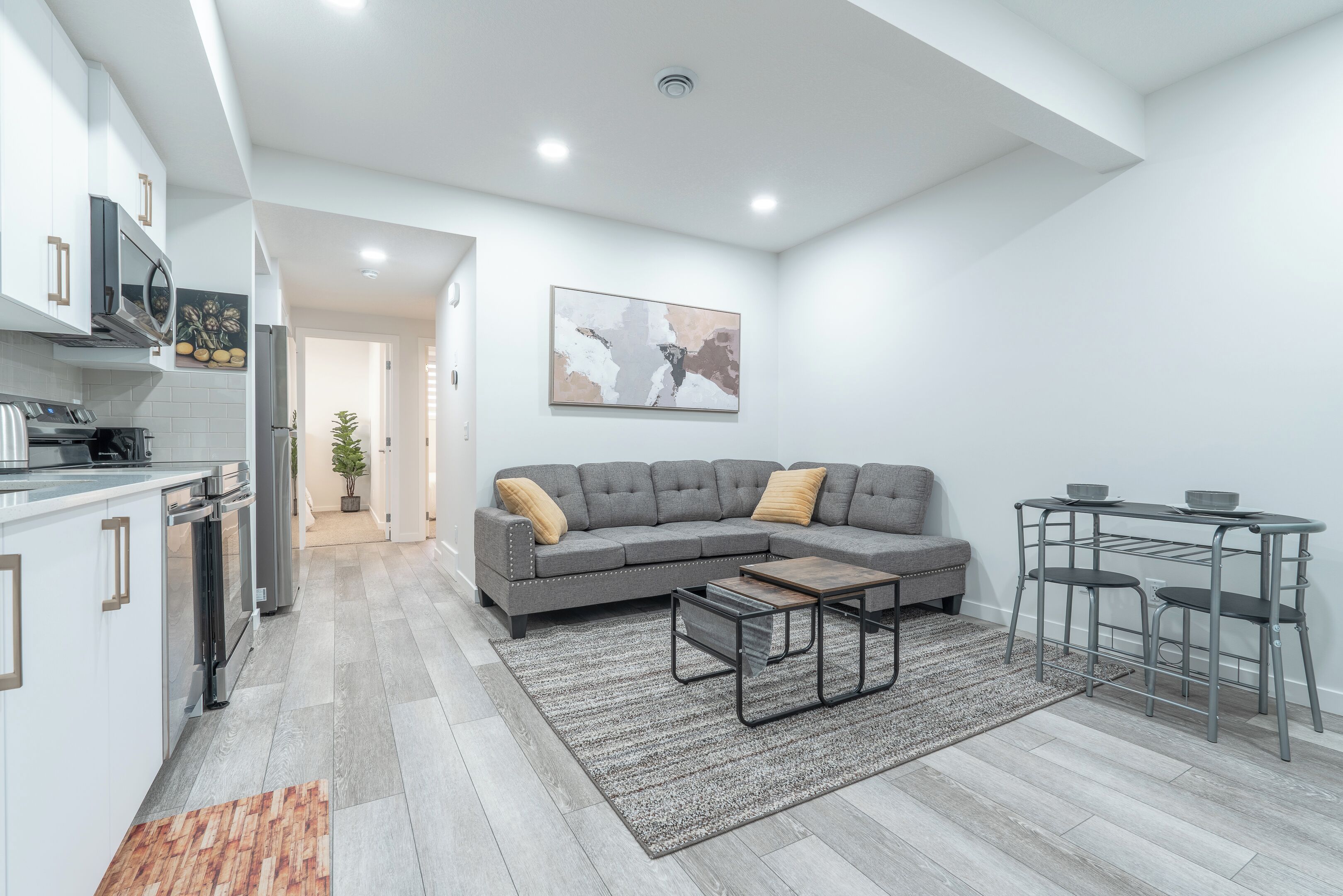 A modern kitchen with white cabinets, a built-in oven, and a microwave.