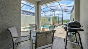 Un espace extérieur aménagé, abrité et doté de sièges, avec vue sur la piscine, un barbecue et des chaises.