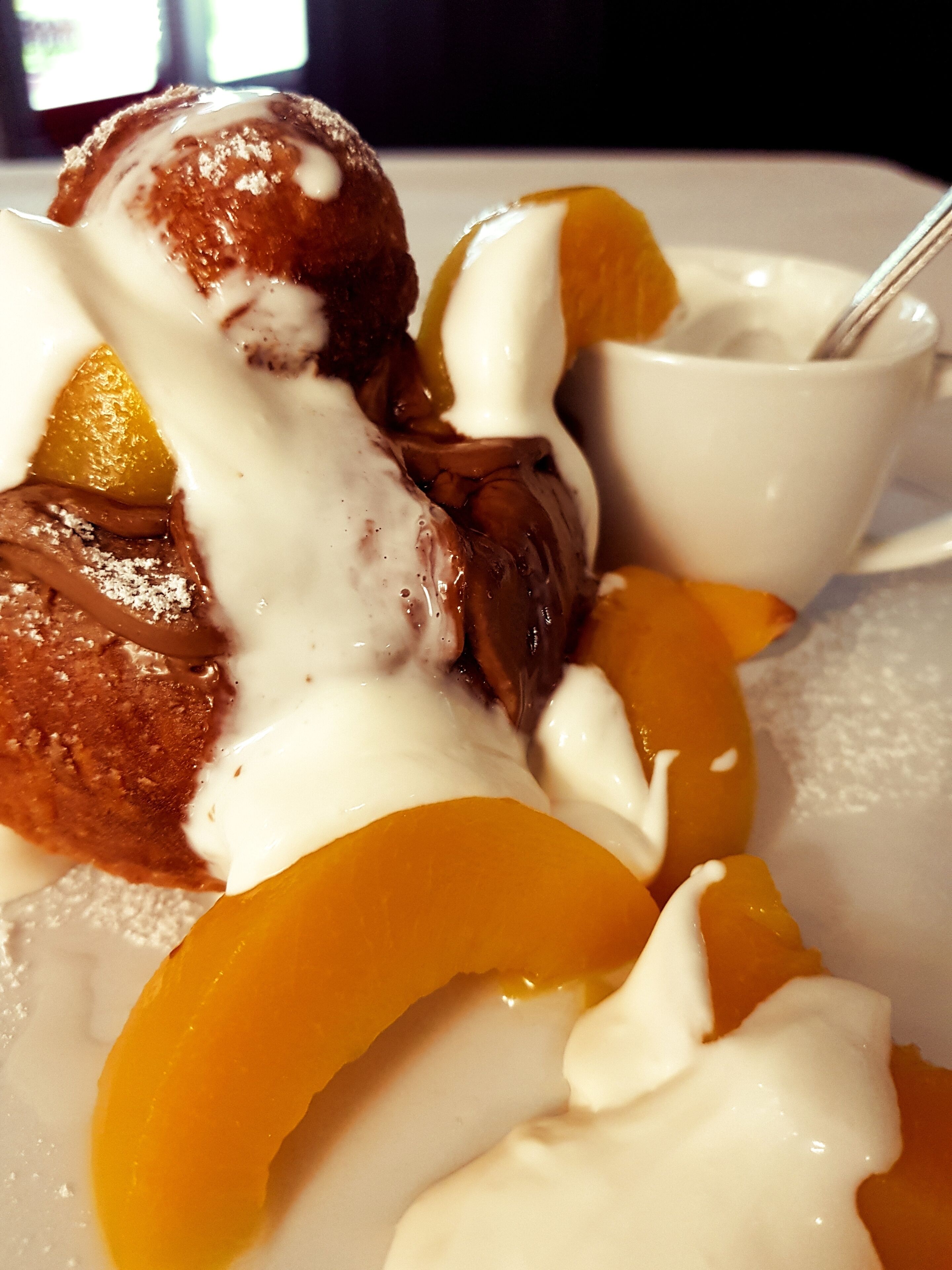 A dessert plate with chocolate-covered pastries, a scoop of ice cream, and slices of peach.